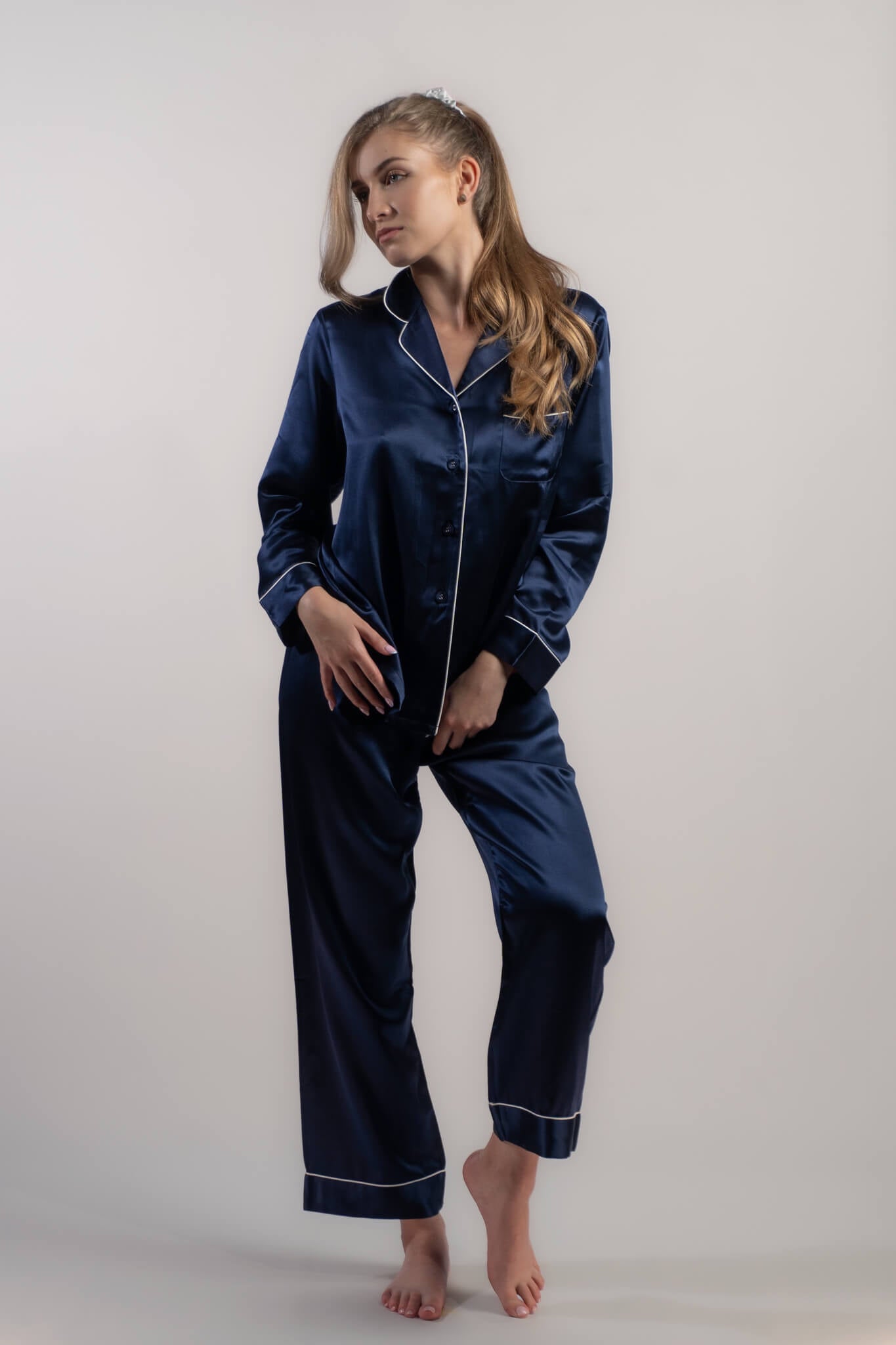 Woman wearing Silk Closet navy blue long pyjama set pants - sitting on couch. 100% mulberry silk. Button up front.